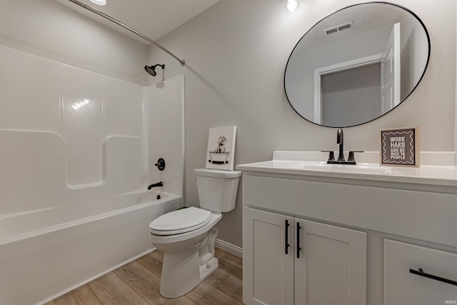 bathroom with visible vents, vanity, wood finished floors, toilet, and shower / bathing tub combination