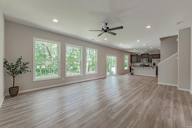 unfurnished living room with baseboards, a ceiling fan, light wood finished floors, and recessed lighting