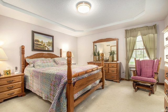 bedroom featuring a tray ceiling, a textured ceiling, and light colored carpet