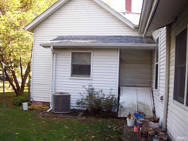 view of side of home with roof with shingles and central AC