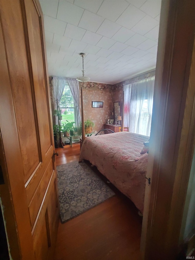 bedroom with wallpapered walls and wood finished floors