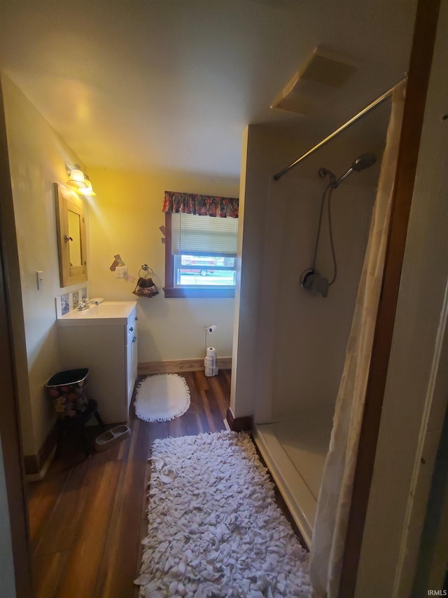 bathroom with vanity, baseboards, a shower with shower curtain, and wood finished floors