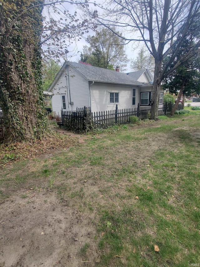 rear view of house with fence, a chimney, and a shingled roof