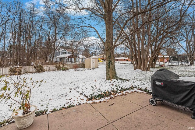 yard covered in snow featuring a residential view, fence, an outbuilding, and a shed