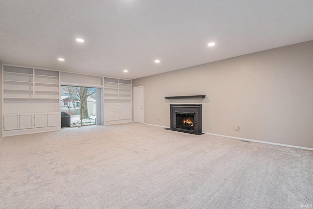 unfurnished living room with carpet, recessed lighting, baseboards, a fireplace with flush hearth, and visible vents