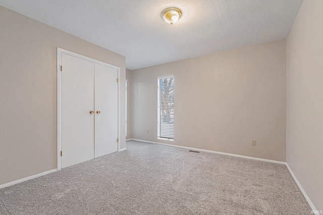 unfurnished bedroom featuring a closet, carpet flooring, baseboards, and visible vents