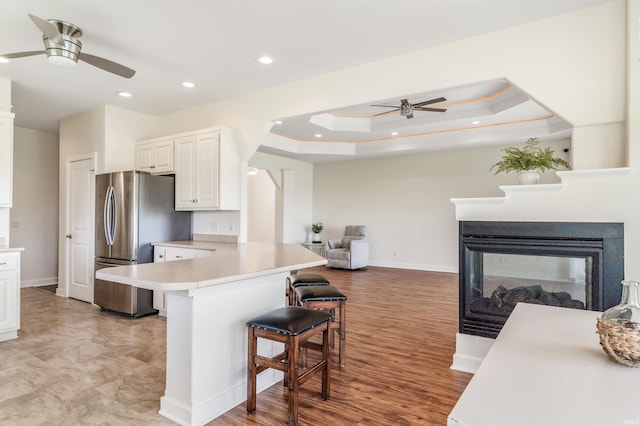kitchen with a ceiling fan, a breakfast bar area, a peninsula, and freestanding refrigerator