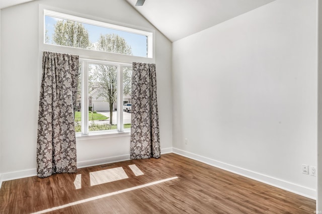empty room with baseboards, visible vents, wood finished floors, and lofted ceiling