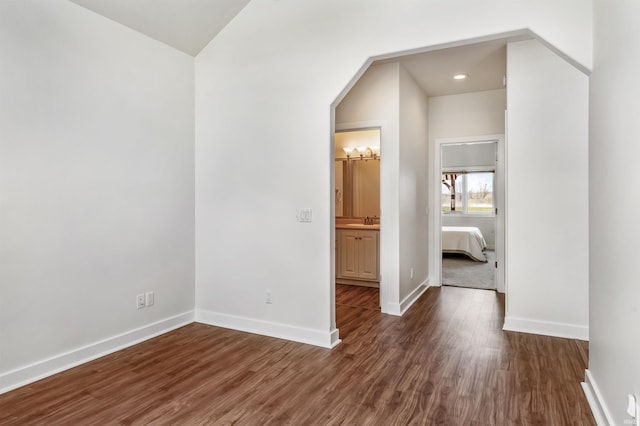unfurnished bedroom featuring recessed lighting, baseboards, a sink, and wood finished floors
