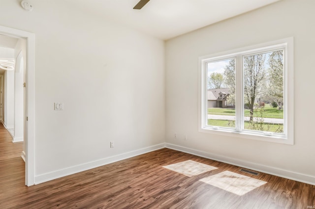 unfurnished room featuring baseboards, wood finished floors, and visible vents