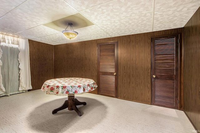 dining room featuring carpet and wooden walls