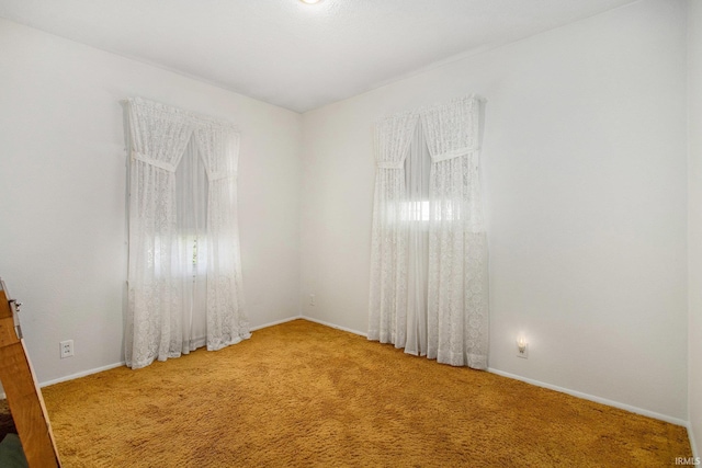 carpeted empty room featuring baseboards