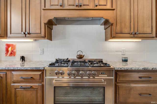 kitchen featuring high end stainless steel range, brown cabinetry, and tasteful backsplash