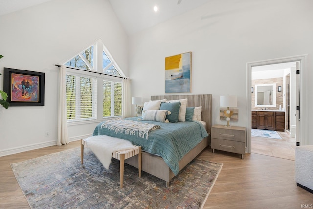 bedroom featuring a sink, high vaulted ceiling, baseboards, and light wood finished floors