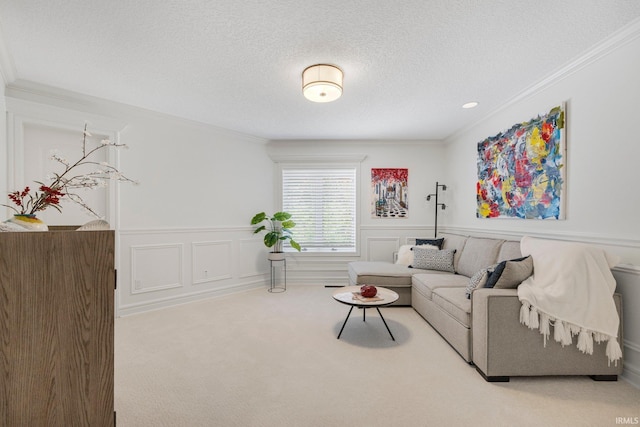 carpeted living area featuring a wainscoted wall, ornamental molding, a decorative wall, and a textured ceiling