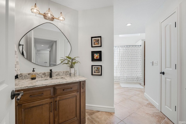 bathroom featuring a shower, vanity, baseboards, and tile patterned flooring