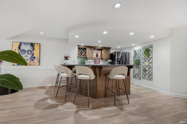 bar with indoor wet bar, recessed lighting, light wood finished floors, and stainless steel fridge with ice dispenser