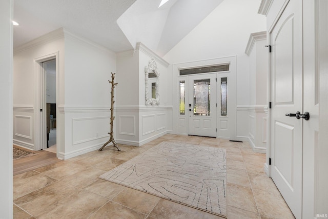 foyer entrance with crown molding, a wainscoted wall, and a decorative wall