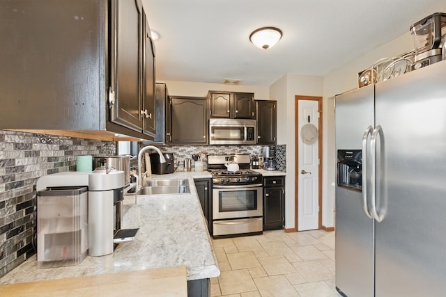 kitchen featuring appliances with stainless steel finishes, tasteful backsplash, dark brown cabinets, a sink, and light countertops