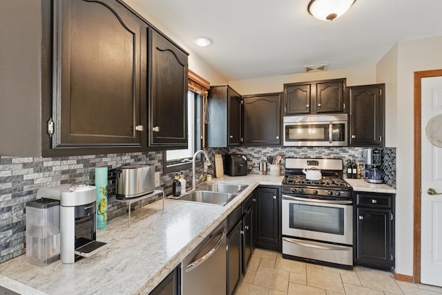 kitchen with a sink, light countertops, decorative backsplash, and stainless steel appliances