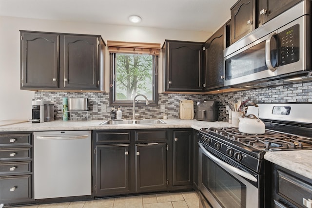 kitchen featuring a sink, appliances with stainless steel finishes, backsplash, and light countertops