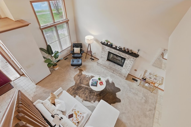 carpeted living room with a towering ceiling and a fireplace