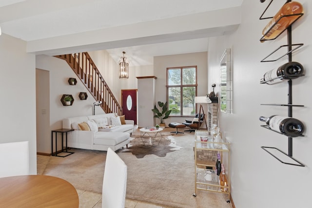 carpeted living area featuring tile patterned flooring, an inviting chandelier, and stairway