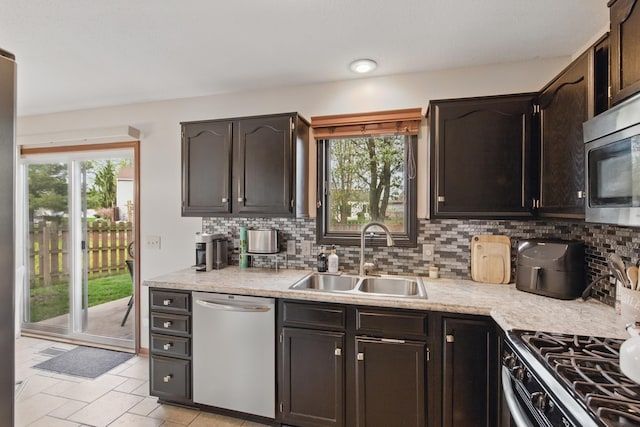 kitchen featuring decorative backsplash, appliances with stainless steel finishes, dark brown cabinets, a sink, and light countertops