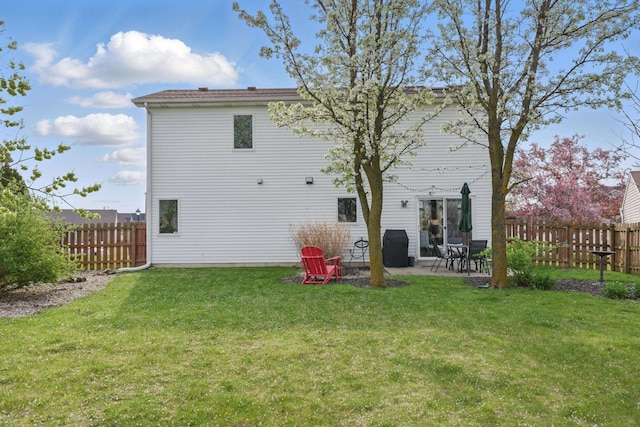 back of house featuring a fenced backyard, a patio, and a lawn