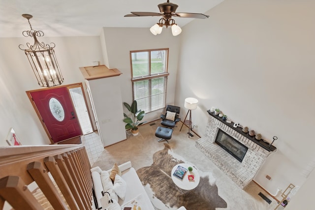living area with ceiling fan with notable chandelier, carpet, and a brick fireplace