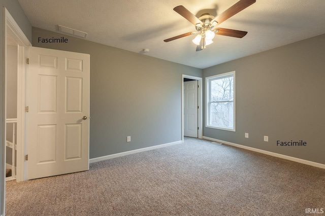 carpeted empty room with visible vents, a textured ceiling, baseboards, and ceiling fan