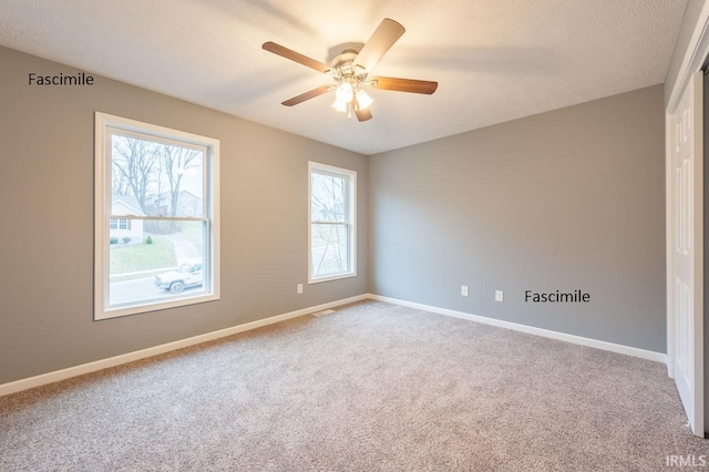 carpeted empty room with baseboards, a textured ceiling, ceiling fan, and visible vents