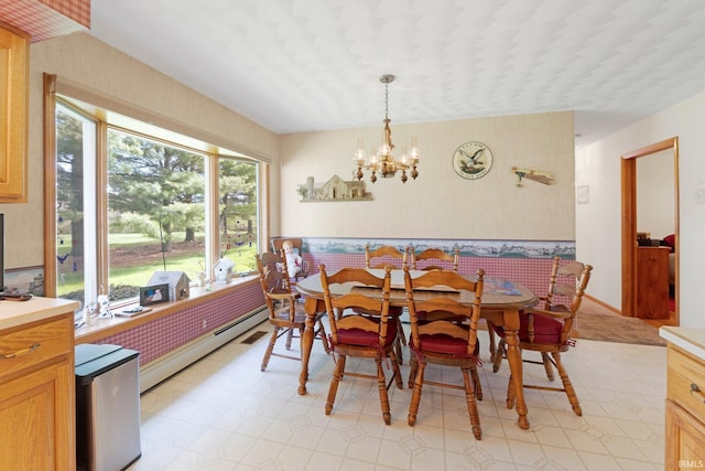 dining area featuring light floors, a baseboard heating unit, and a chandelier