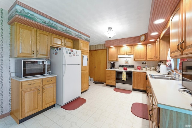 kitchen with light countertops, freestanding refrigerator, stainless steel microwave, under cabinet range hood, and range with electric stovetop
