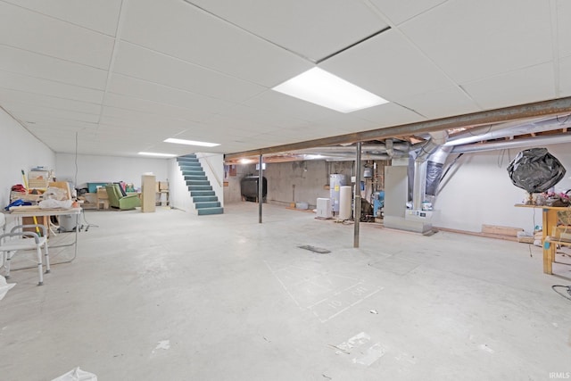 below grade area with heating unit, heating fuel, water heater, and stairs
