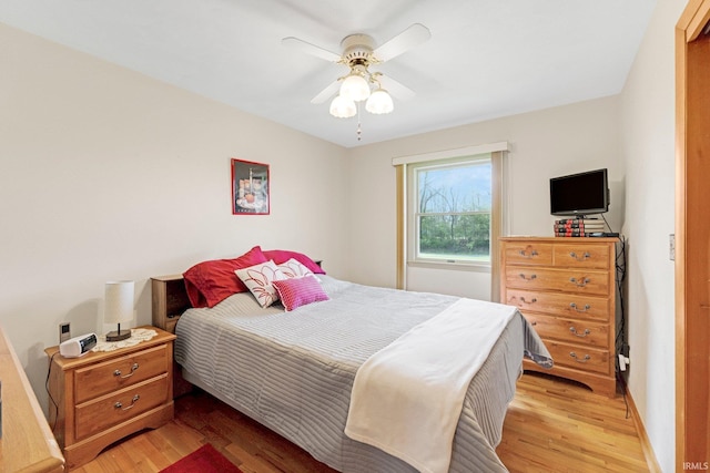 bedroom with a ceiling fan, baseboards, and light wood-style flooring