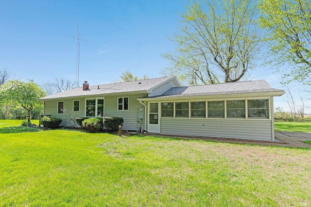 back of house featuring a sunroom, a yard, and a chimney