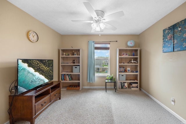 living area featuring carpet flooring, a ceiling fan, baseboards, and a textured ceiling