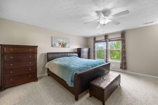 bedroom with visible vents, light carpet, baseboards, a textured ceiling, and a ceiling fan