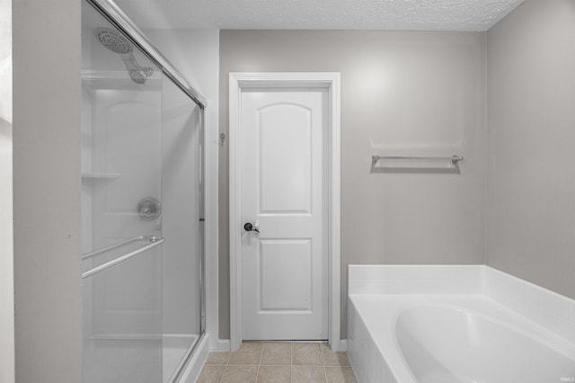 full bathroom featuring a textured ceiling, tile patterned flooring, a stall shower, and a bath