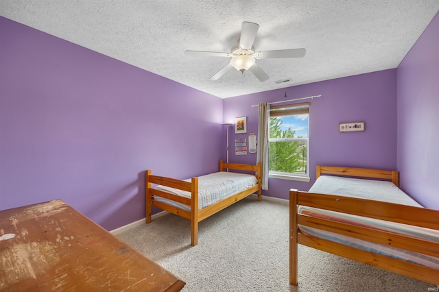 bedroom featuring carpet flooring, a textured ceiling, baseboards, and visible vents