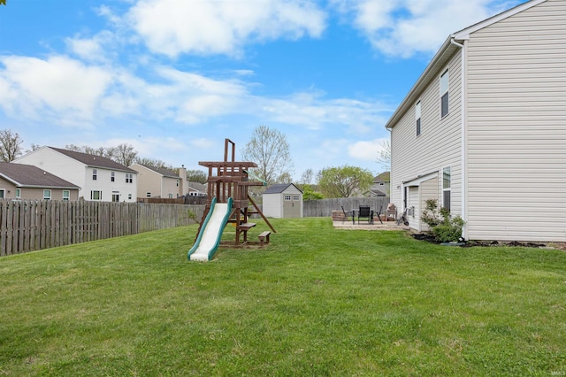 view of yard featuring a residential view, a fenced backyard, an outdoor structure, a playground, and a storage unit