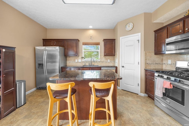 kitchen featuring decorative backsplash, a breakfast bar area, a center island, a sink, and stainless steel appliances