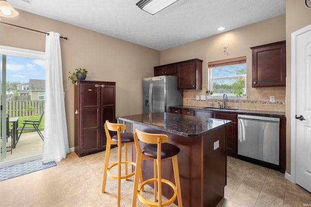 kitchen with appliances with stainless steel finishes, a breakfast bar, a sink, a center island, and tasteful backsplash