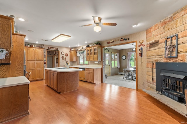 kitchen featuring light wood-style floors, dishwashing machine, a center island, light countertops, and a ceiling fan