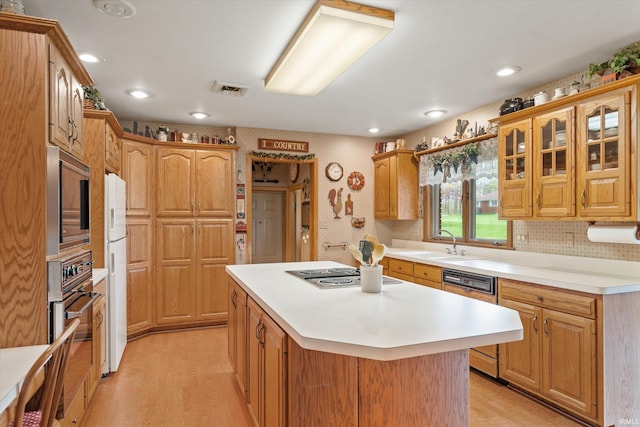 kitchen with appliances with stainless steel finishes, a center island, light wood-type flooring, a sink, and light countertops