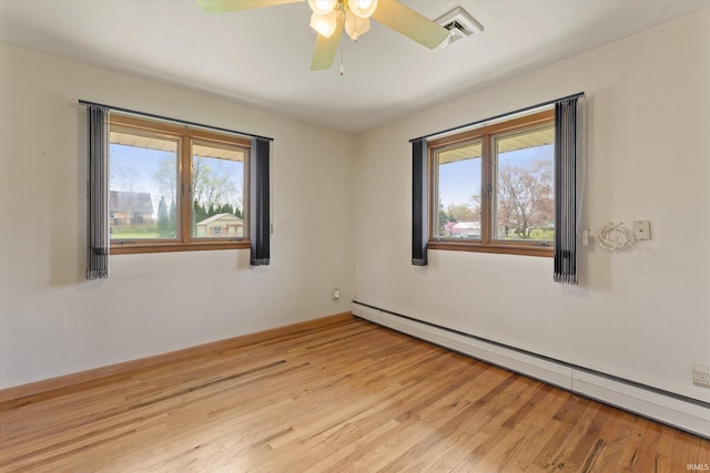 spare room with ceiling fan, visible vents, light wood finished floors, and a baseboard radiator