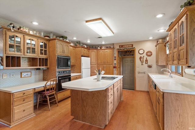 kitchen with light wood-style floors, a sink, a kitchen island, and black appliances