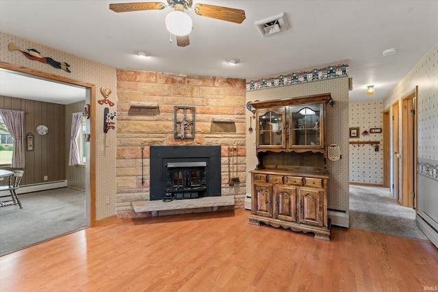 living room with a ceiling fan, wallpapered walls, wood finished floors, and visible vents