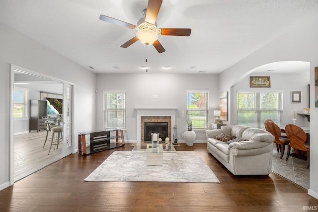 living area featuring arched walkways, dark wood-style flooring, and a wealth of natural light